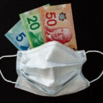 A Face Mask with Canadian Dollar bills on a black background.